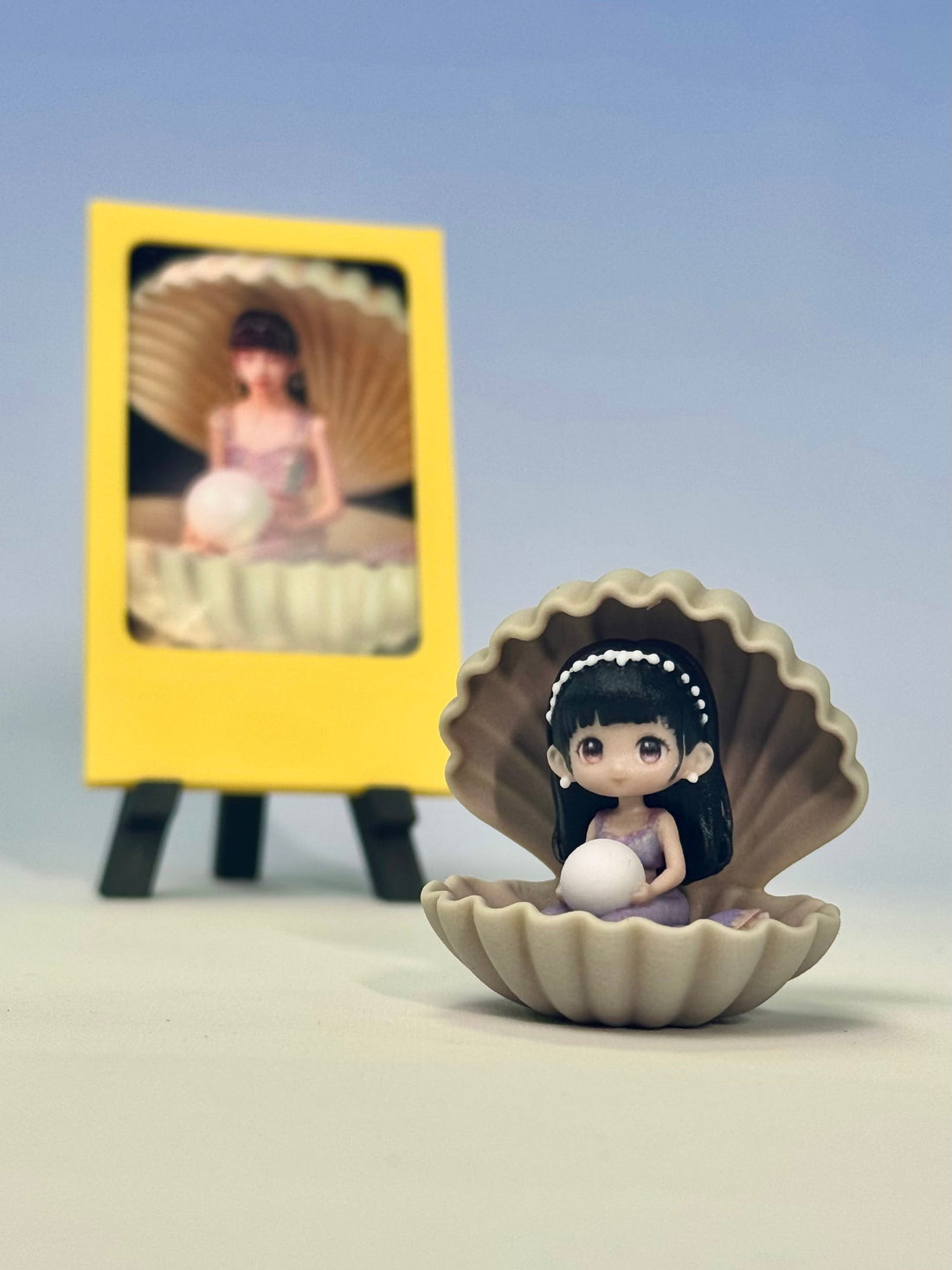 Custom figure in a ridged shell holding a pearl-like orb in a lavender dress