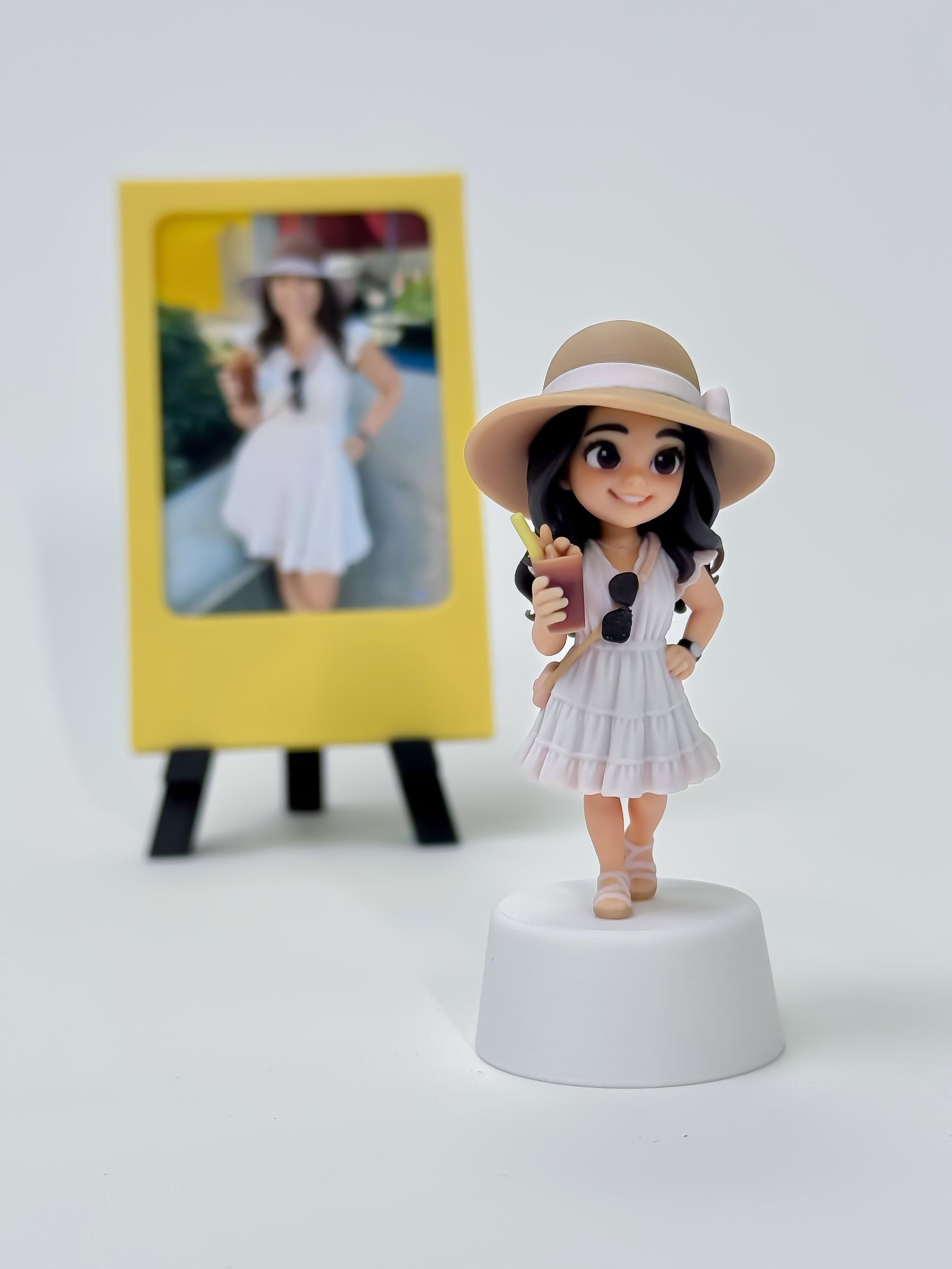 Finished personalized figure of Michelle Morgan in a white dress and sunhat beside the reference photo
