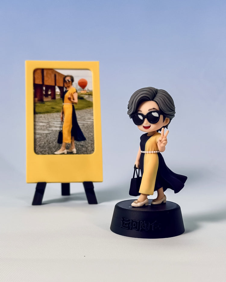Finished custom travel figure beside a simple yellow photo frame, preserving the color-block dress and peace-sign pose